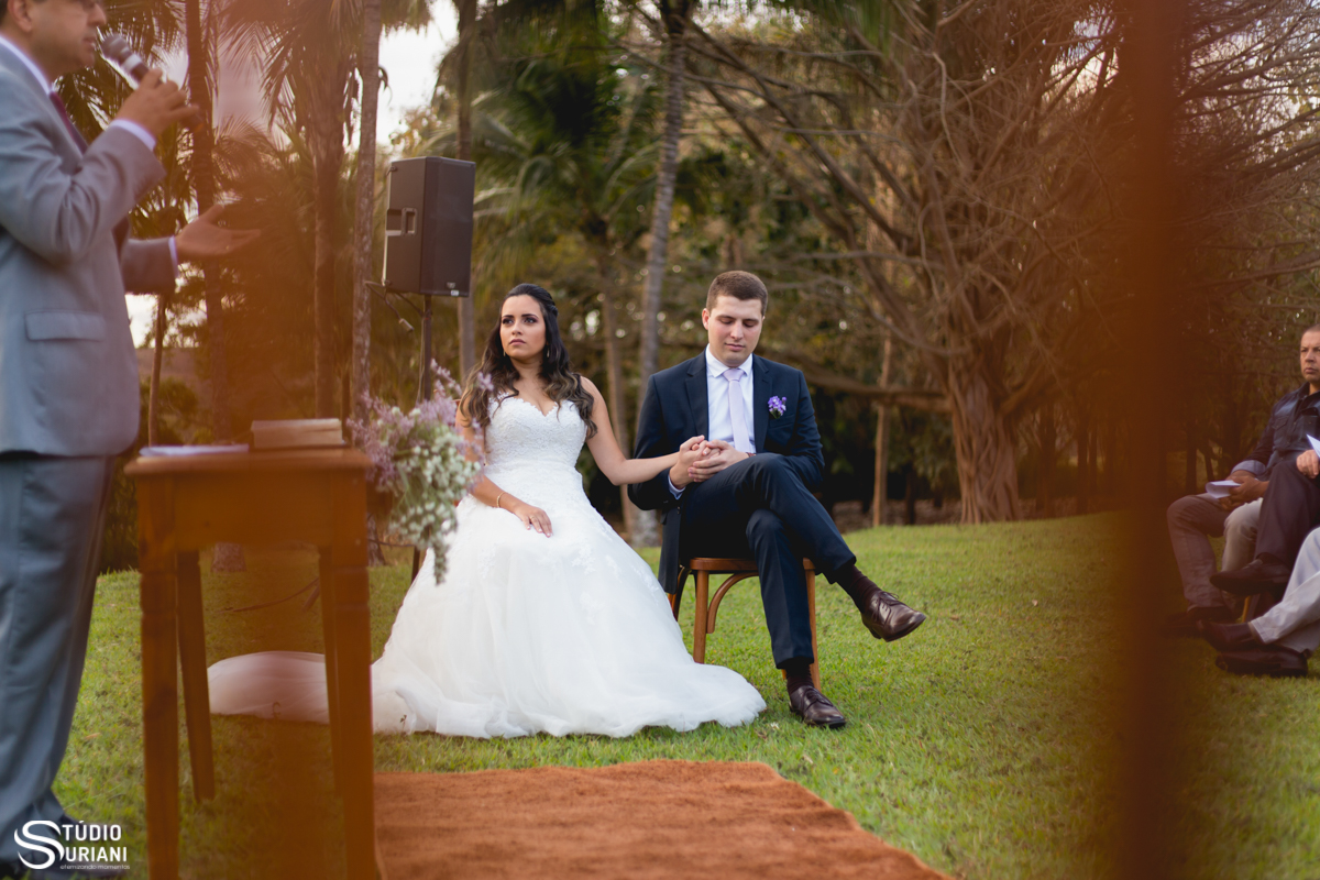 noivo acariciando a mão da noiva no altar em casamento ao ar livre