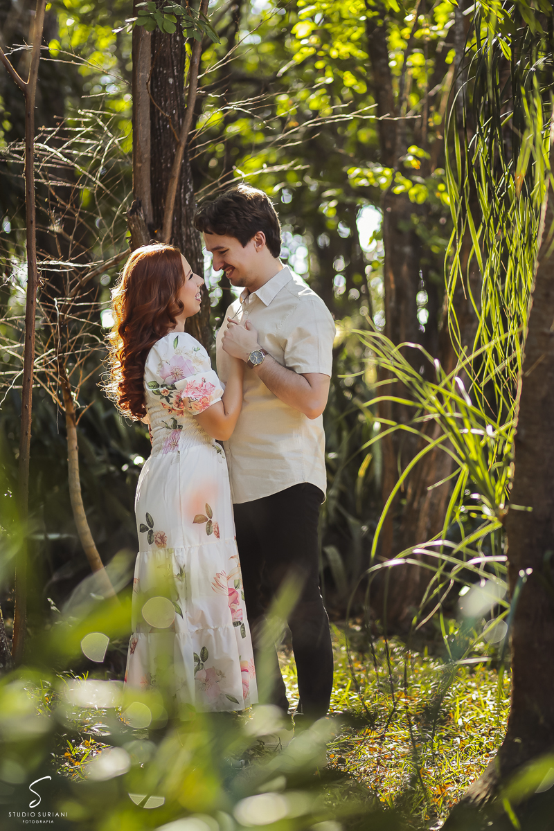 Ligação de coração entre casal, noivos com roupas claras em meio a natureza 