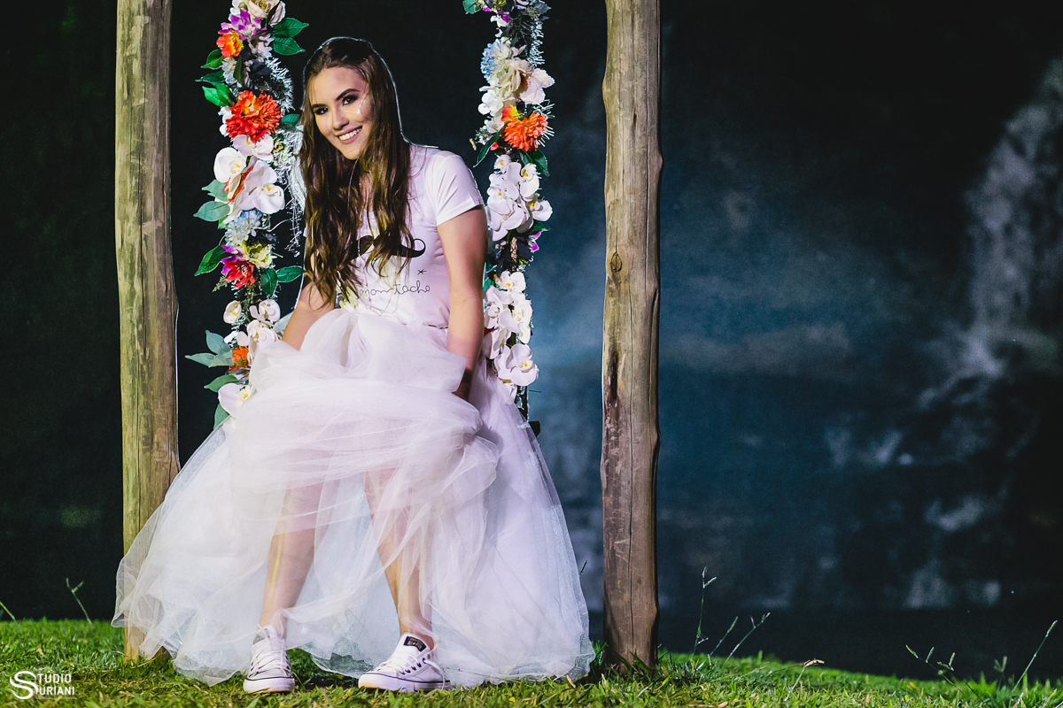 debutante sentada em balanço com flores e vestido tule