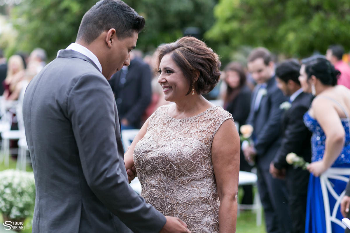 Mãe emocionada entrando com o noivo com terno cinza no casamento ao ar livre em Uberlândia 