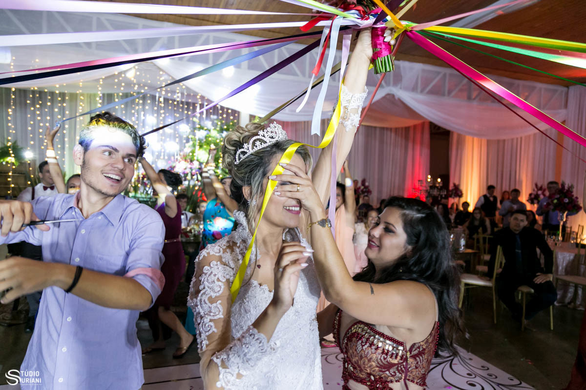 Noiva Karol com buque de fitas cortando com a ajuda dos primos 