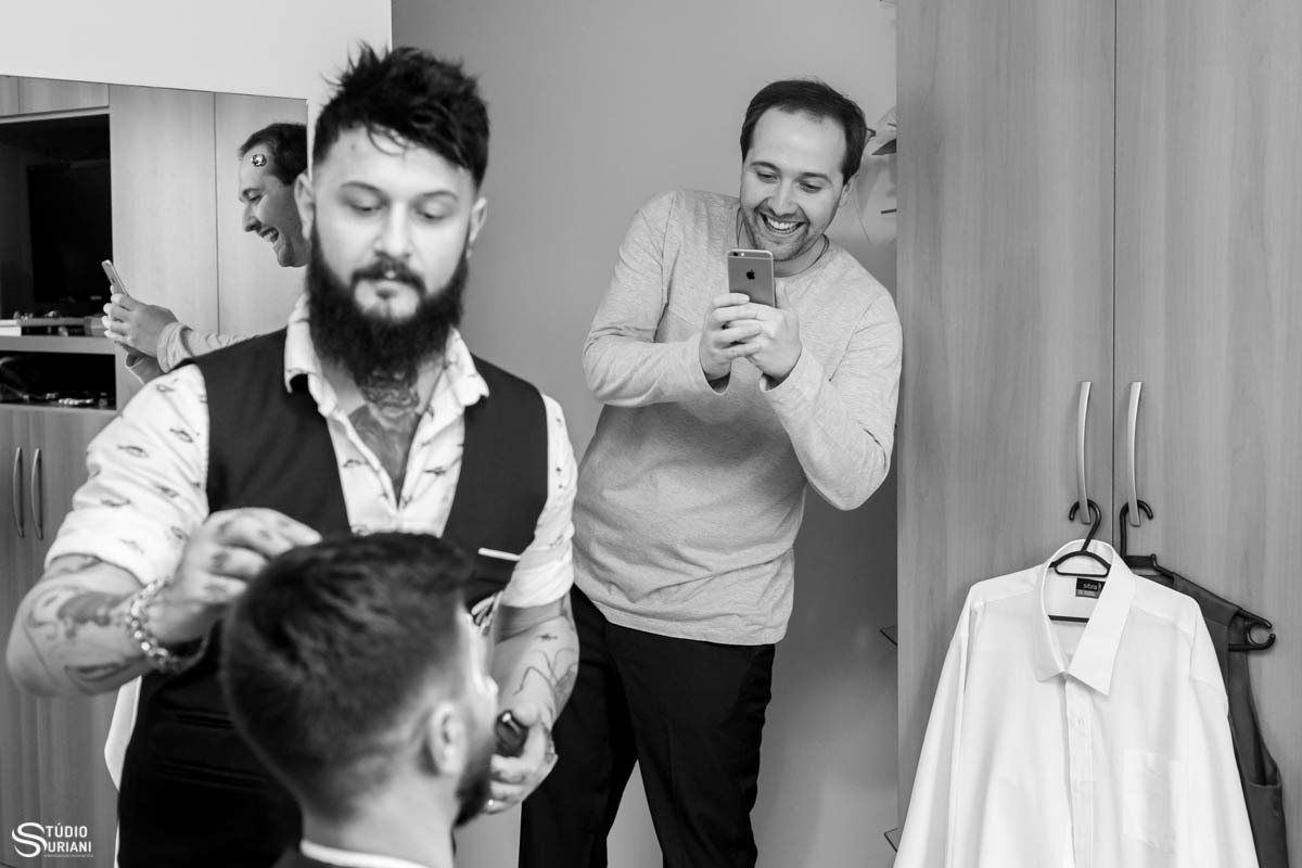 Amigo do noivo sacaneando o noivo tirando fotos dele sendo maquiado 