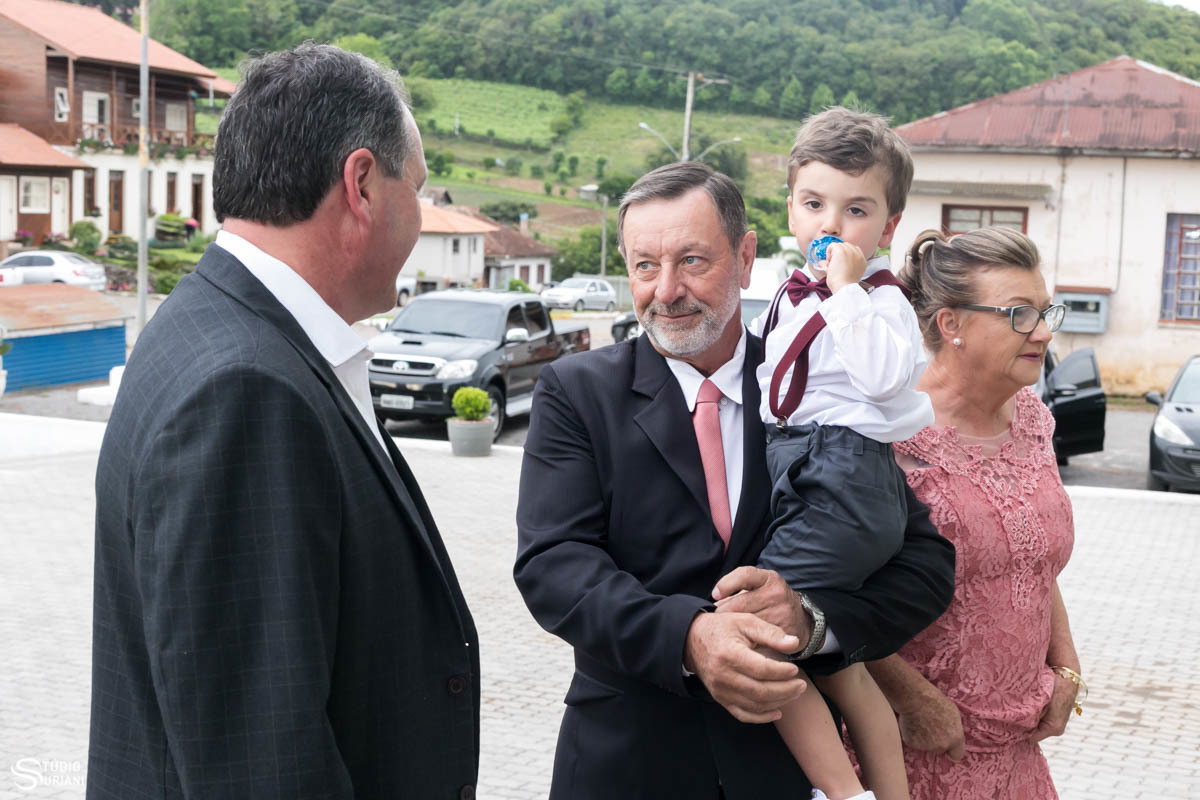 Pai do noivo com o netinho na porta da igreja antes do casamento 