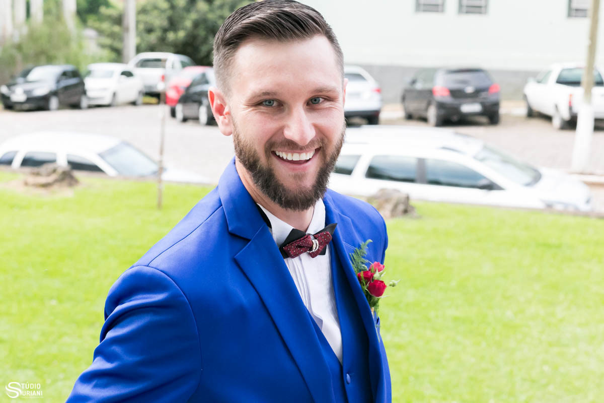 Noivo sorrindo de nervosismo antes de entrar na igreja para se casar na igreja onde ele foi batizado 