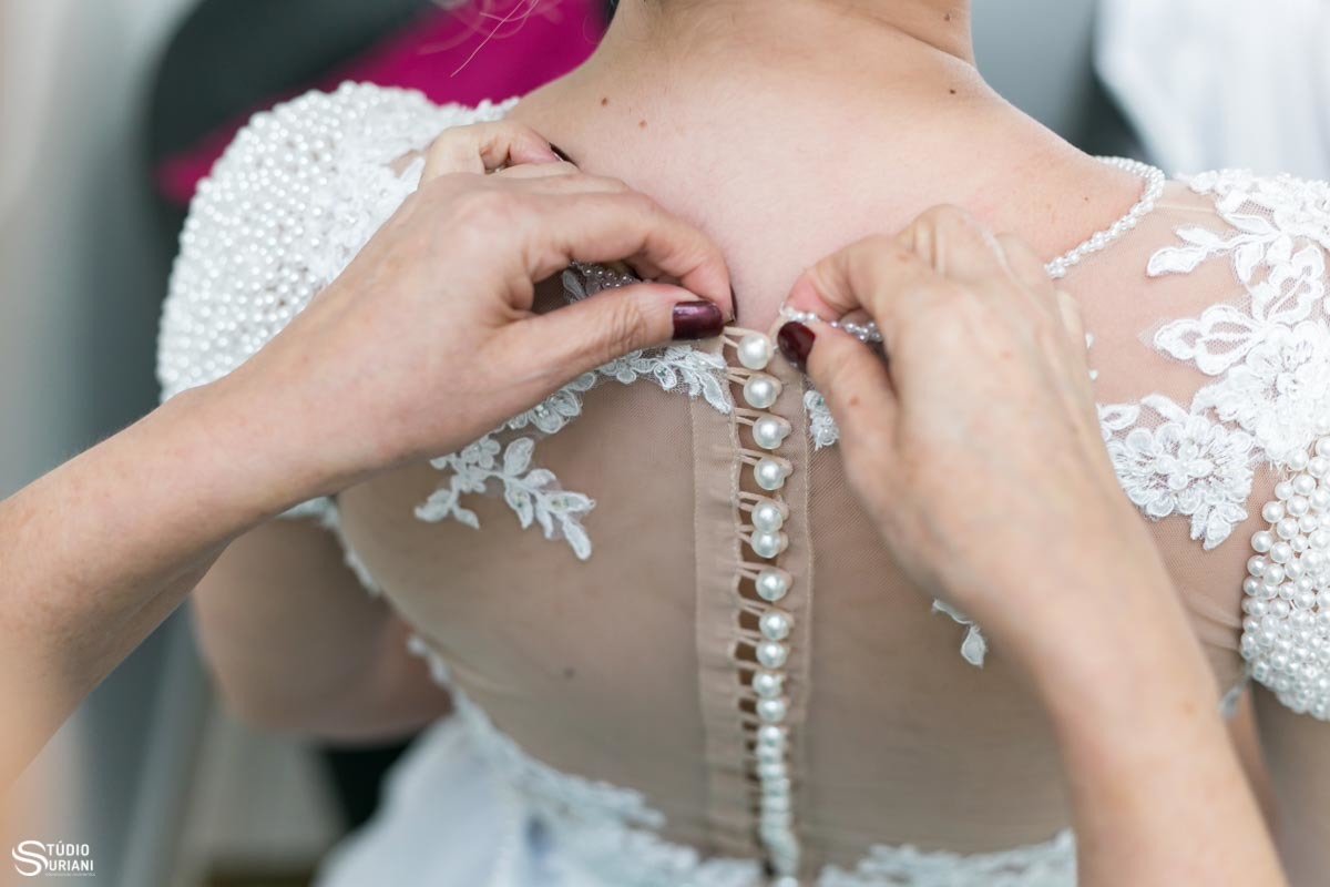 mãe abotoando o vestido da filha