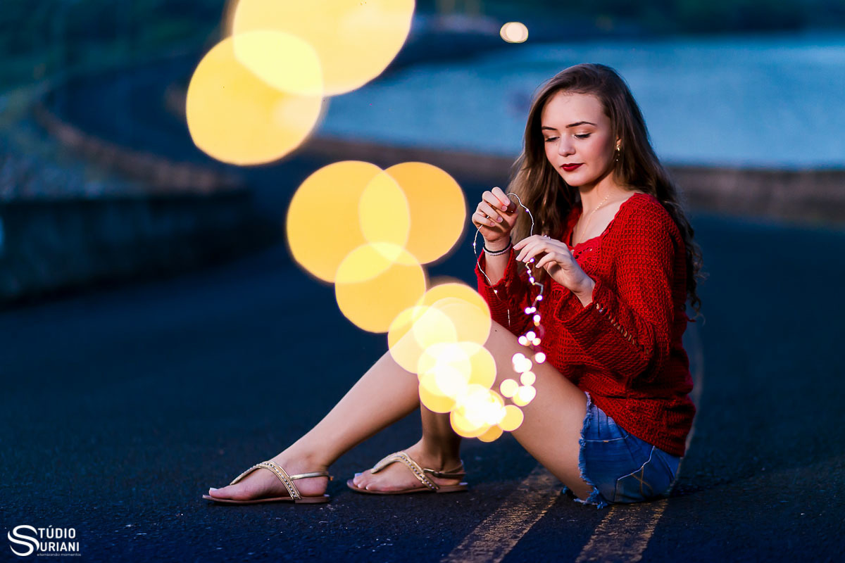 Foto com luzes de natal fazendo um efeito lindo na fotografia de 15 anos com blusa linda vermelha de crôche