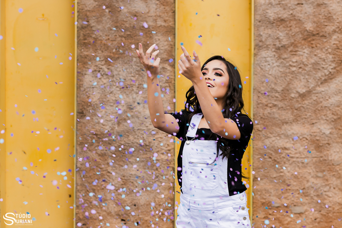 Fotografia de 15 anos estilo menininha com macacão branco e jogando confete como no carnaval 2019 musica do carnaval 2019