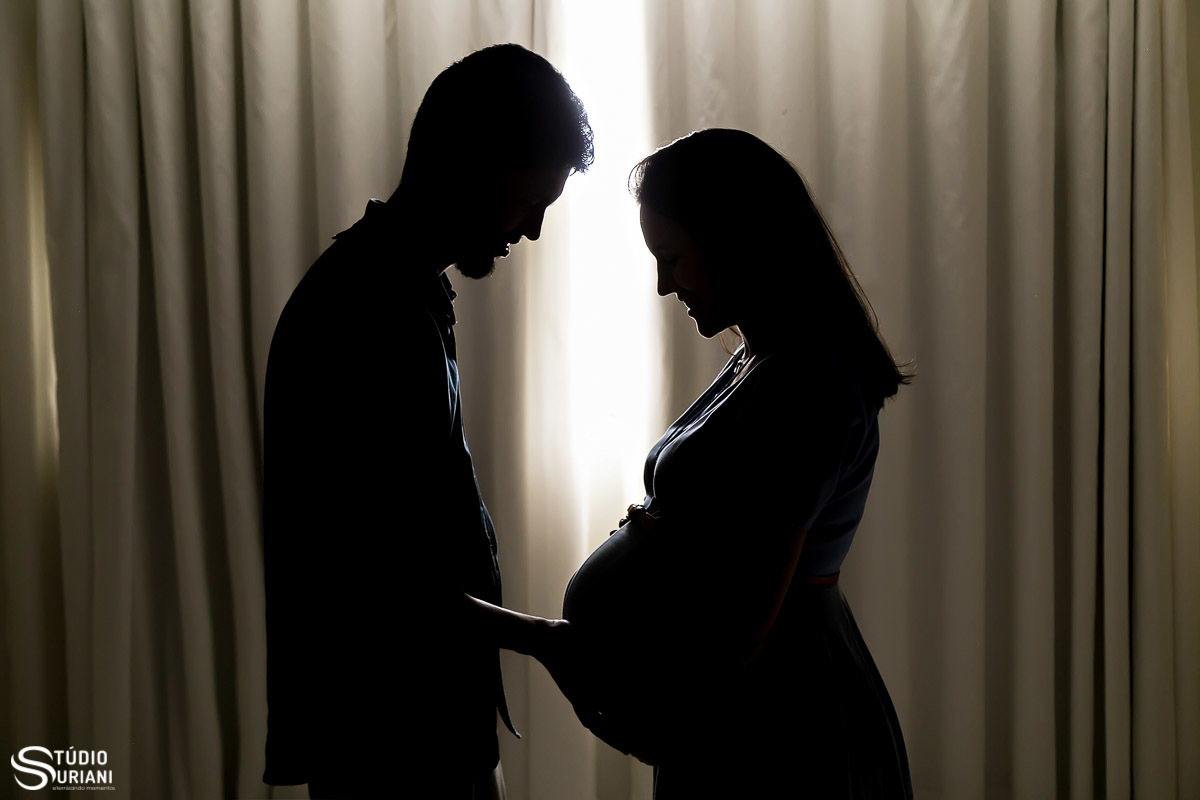 Silhueta do casal gestante em cortina do apartamento do casal religioso 