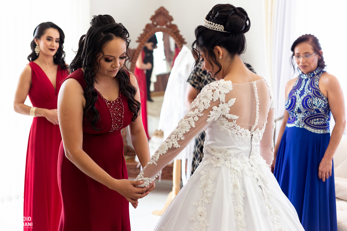Irmã ajudando a noiva a vestir o vestido