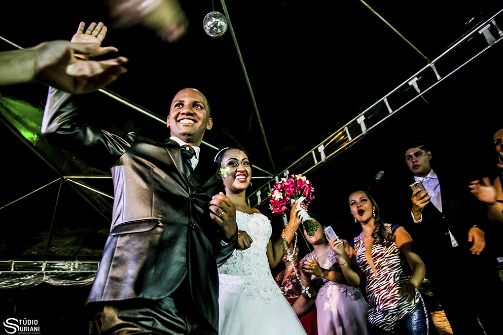 entrada dos noivos na recepção com muita alegria e buque rosa e terno slim