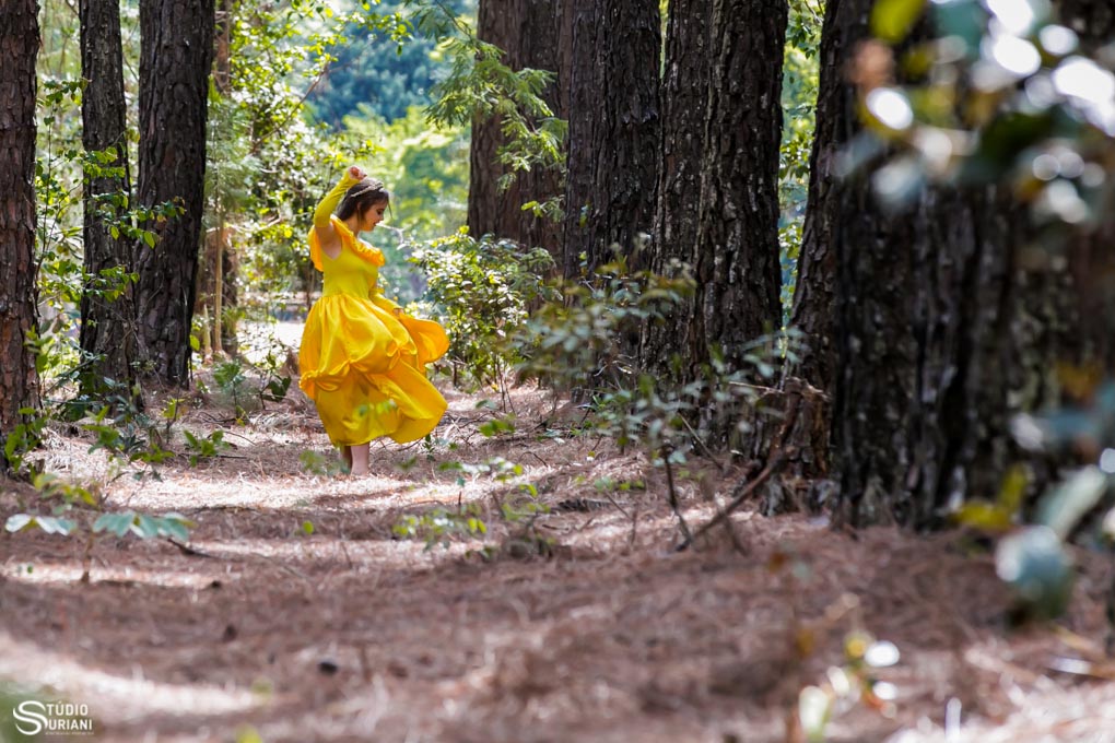 dançando em meio as arvores no ensaio fotográfico com vestido amarelo