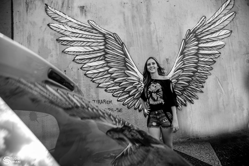 debutante com asas de anjo em muro pichado