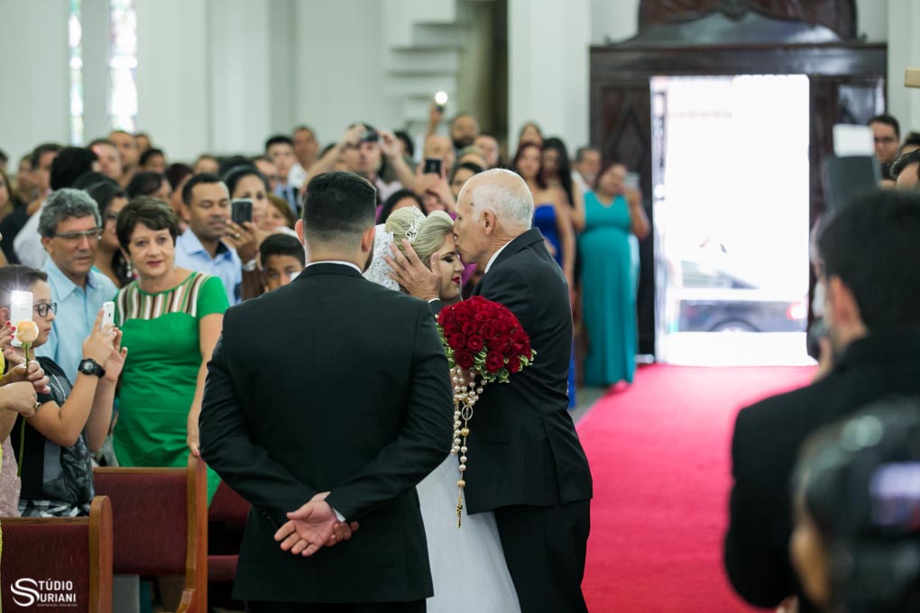 pai entregando a filha no altar com um braijo na testa e tapete vermelho