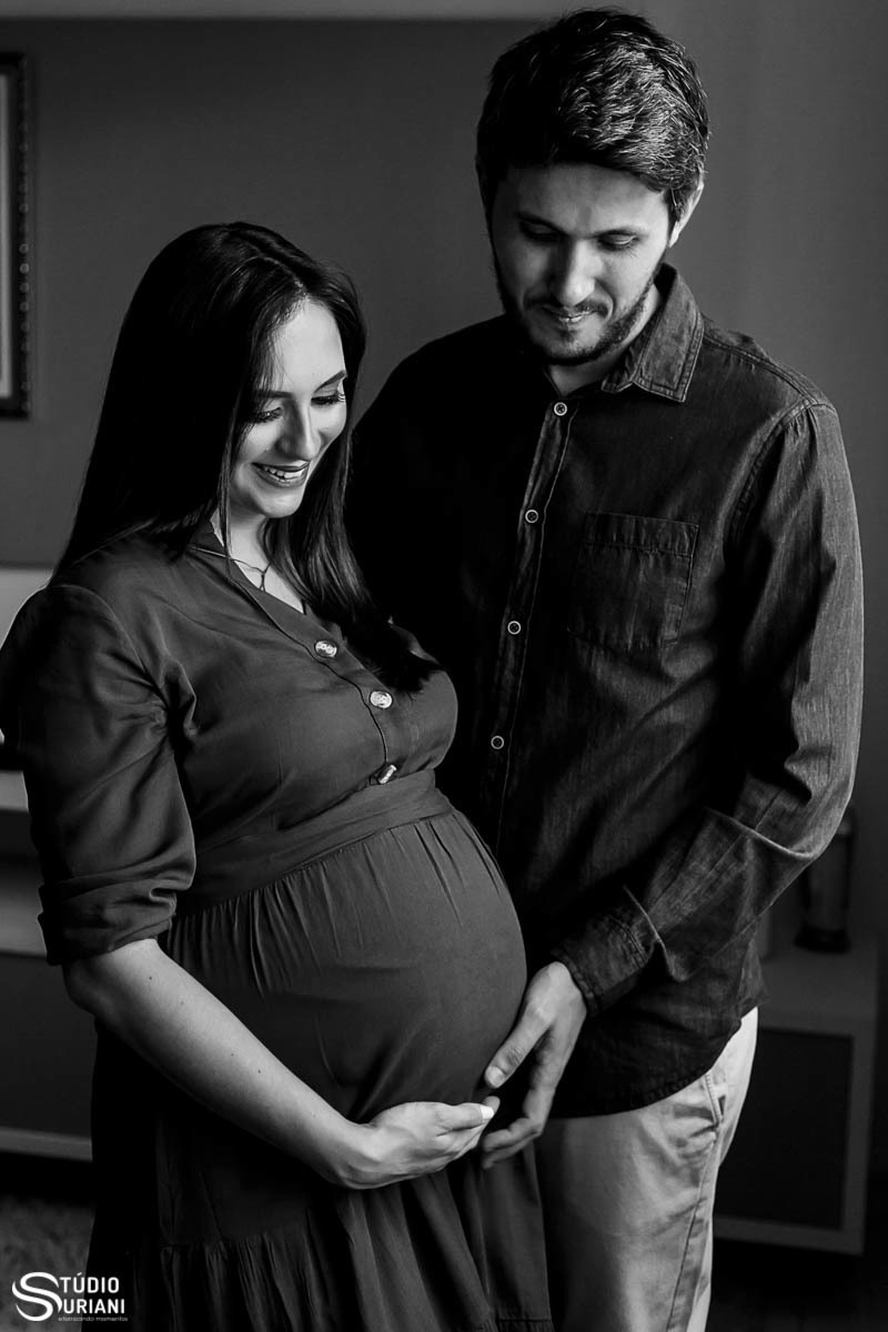 Foto preta e branca de casal gravido de gêmeos sendo fotografado em casa 