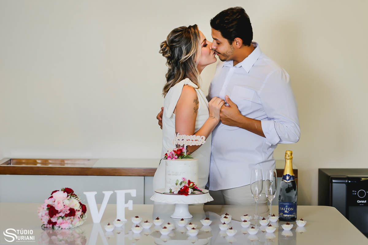 Beijo de noiva com bolo e docinhos em casa e buque de flores simples