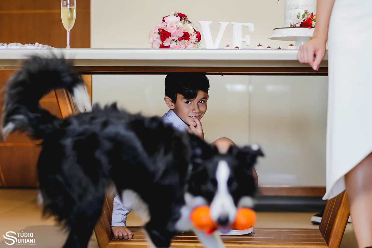 filho da noiva debaixo da mesa com cachorro brincando com mordedor laranja 
