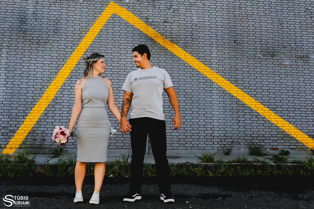 Noivos dentro do triangulo, simbolizando casa amarela com noivos vestindo roupas simples 