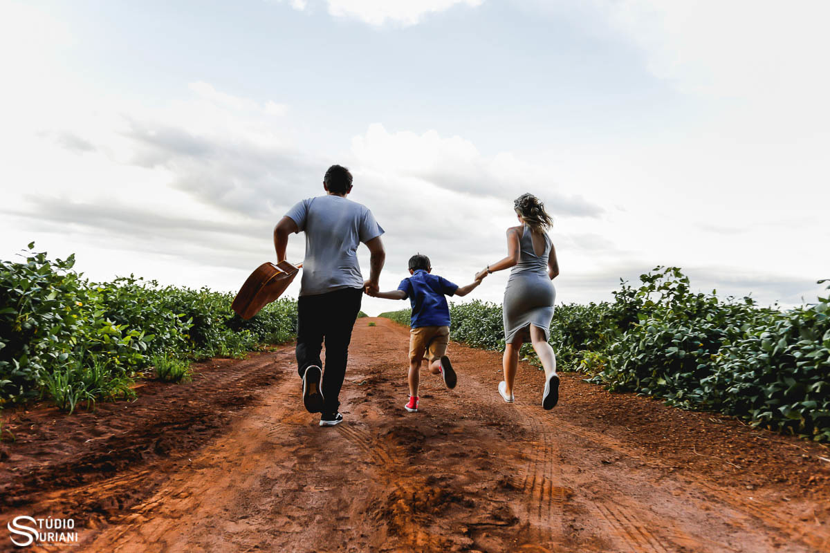 Família correndo com violão na mão do noivo em estrada de terra 