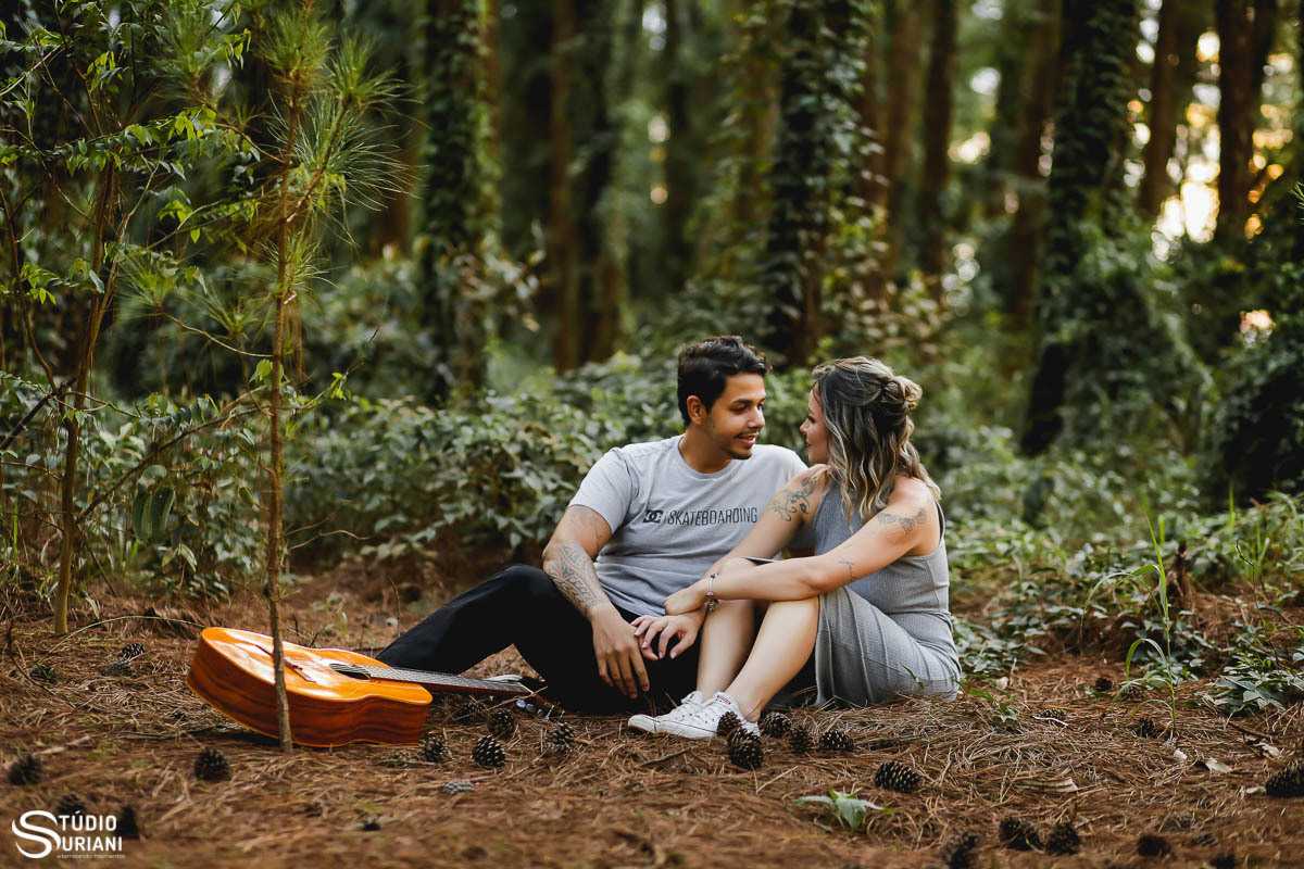 Sentados em meio a floresta olhando um para o outro com violão de lado 