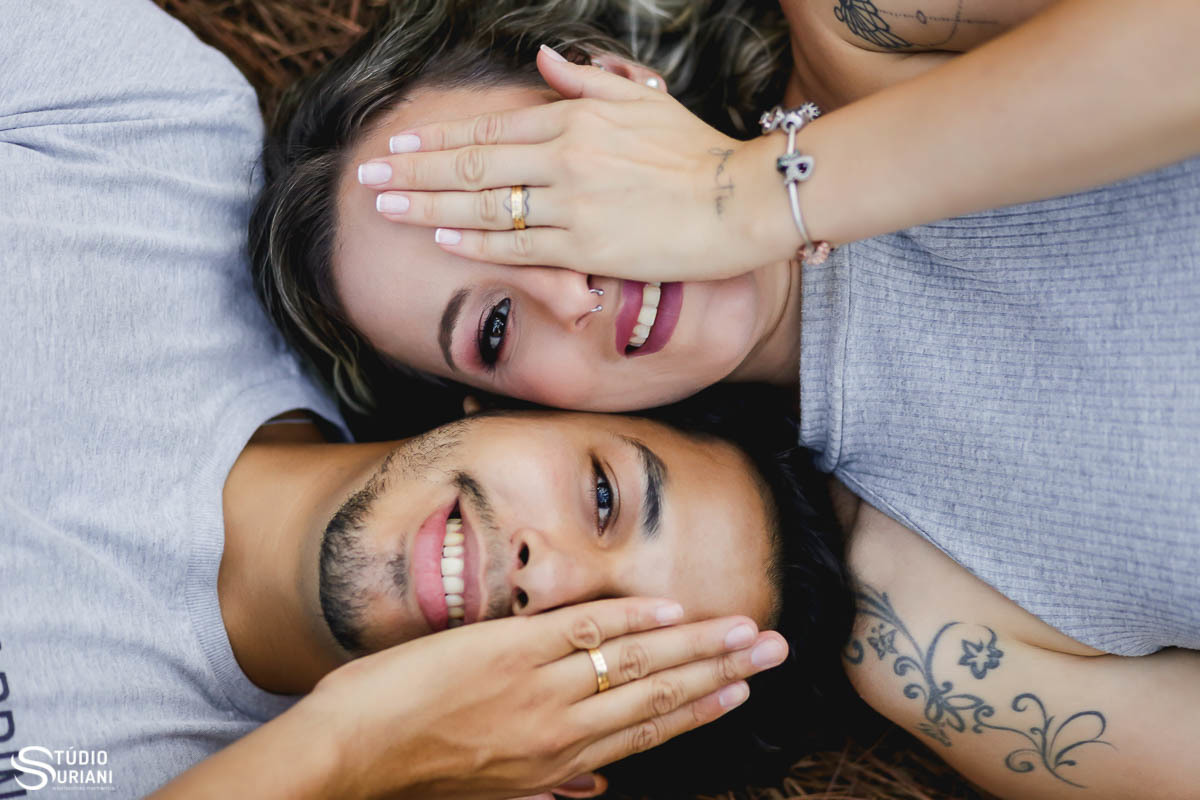 NOivos com seus rostos tampados pelas suas mãos com aliança de casametno 