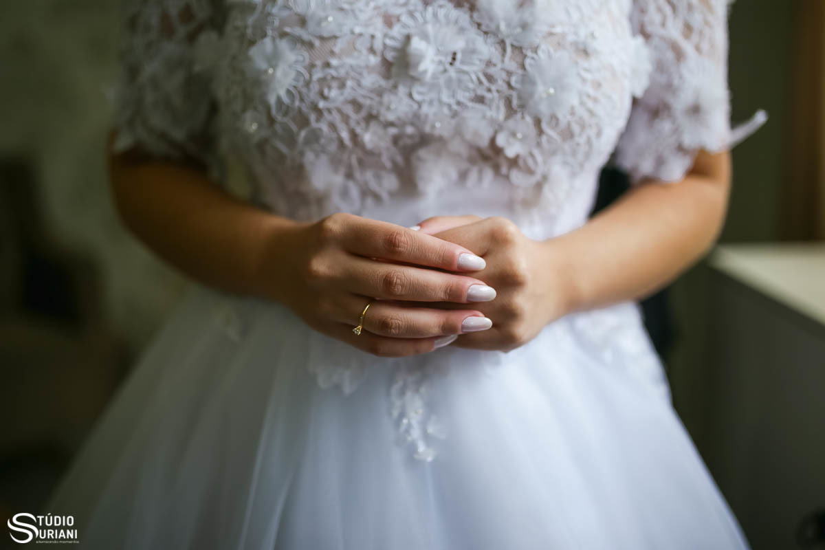 Detalhe de mão da noiva ao colocar o vestido lindo 