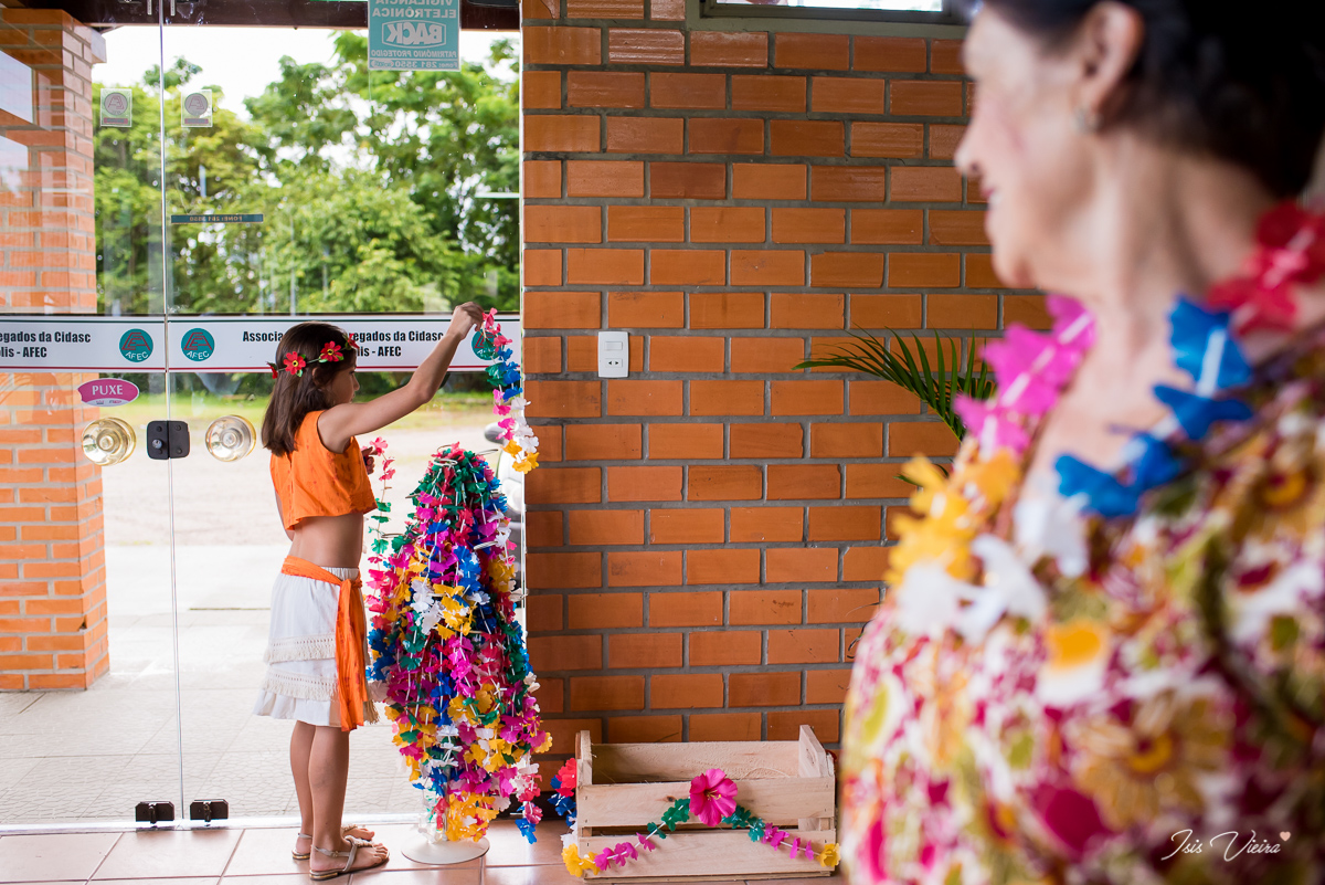 avó olhando atentamente a neta aniversariante pegando colares havaianos coloridos para dar de brinde aos seus convidados da sua festa infantil realizada em florianopolis