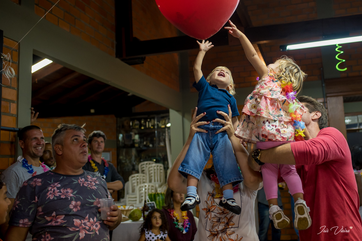 pais e crianças curtindo felizes a brincadeira de pegar nos balões na festa infantil de aniversario da moana em florianopolis com registro da fotografa de festa infantil e familia isis vieira