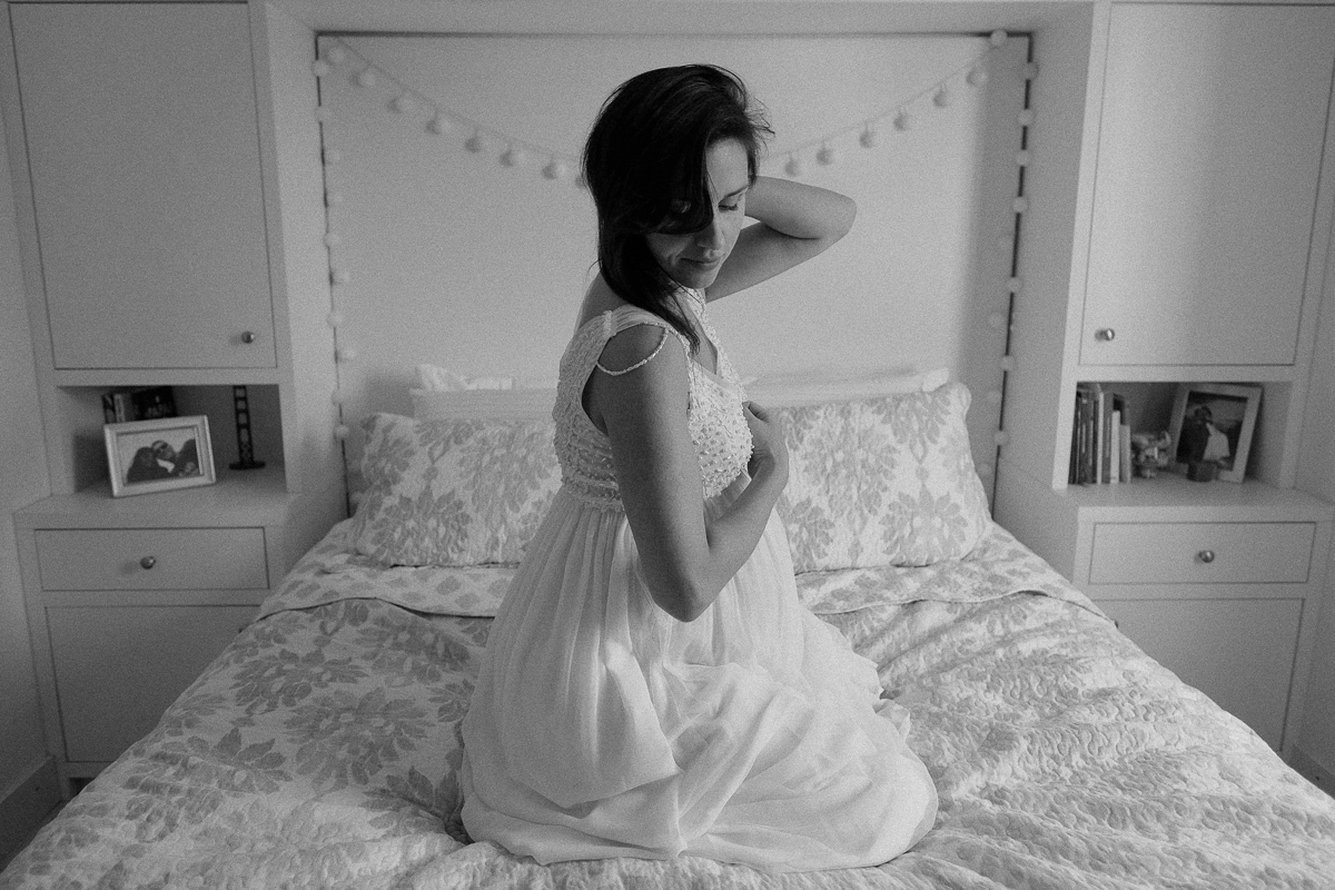 a gestante flavia posa para o seu ensaio fotografico de gestante sentada na cama de casal de seu quarto em florianopolis sc