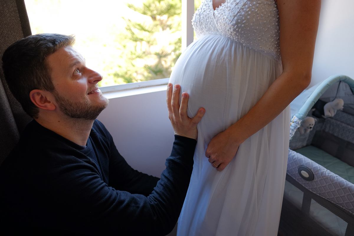momento emocionante que o pai faz carinho na barriga da gestante flavia estacio e olha pra ela com amor e alegria em registro fotografico feito pela fotografa de familias e gestantes isis vieira em florianopolis sc