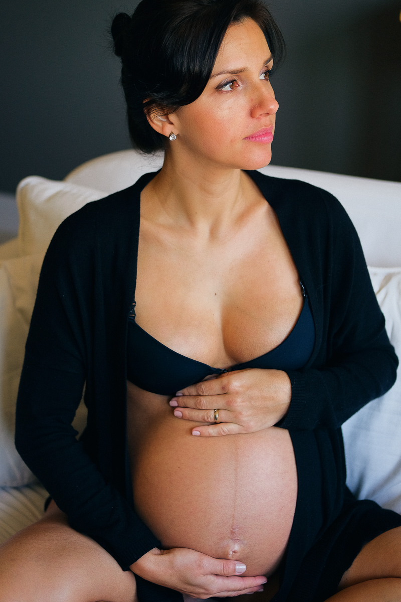 a gestante flavia veste um lindo conjunto preto de langerie e  toca com carinho em sua barriga num momento cheio de amor e carinho em registro fotografico feito por isis vieira fotografia