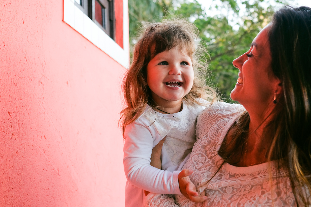  filha sorri no colo da mãe num  momento de alegria e amor registrado pela fotografa de família Isis Vieira em ensaio de família realizado em florianopolis