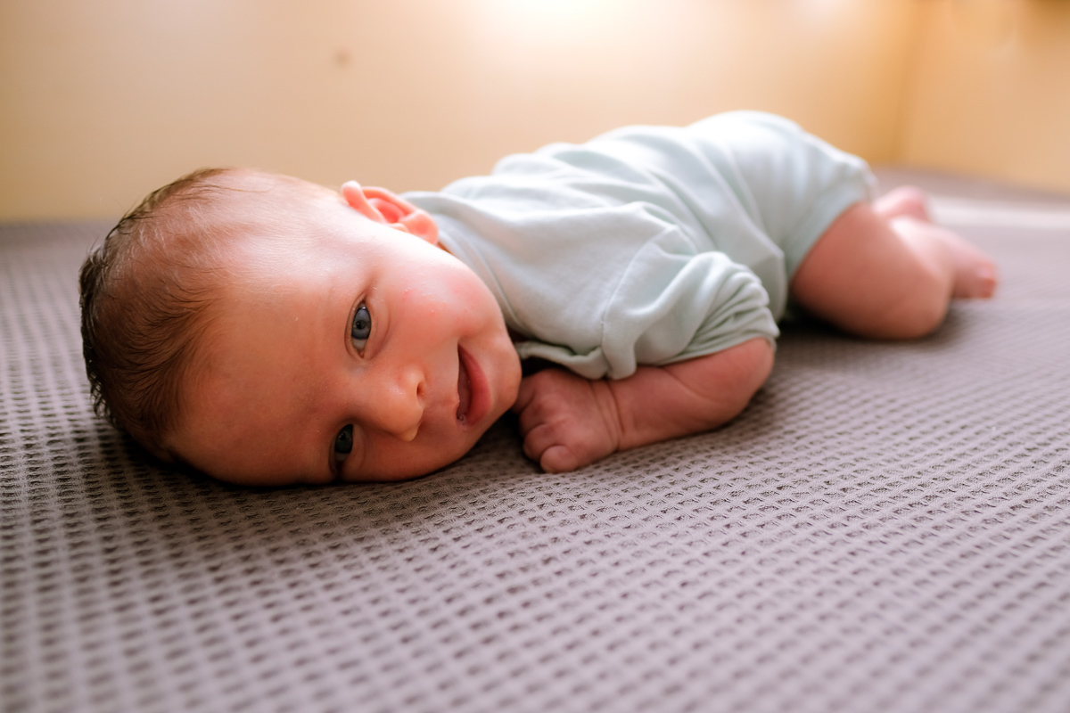 deitado na cama e sorridente o recém nascido francisco ficou para o seu ensaio newborn lifestyle na sua casa em florianopolis