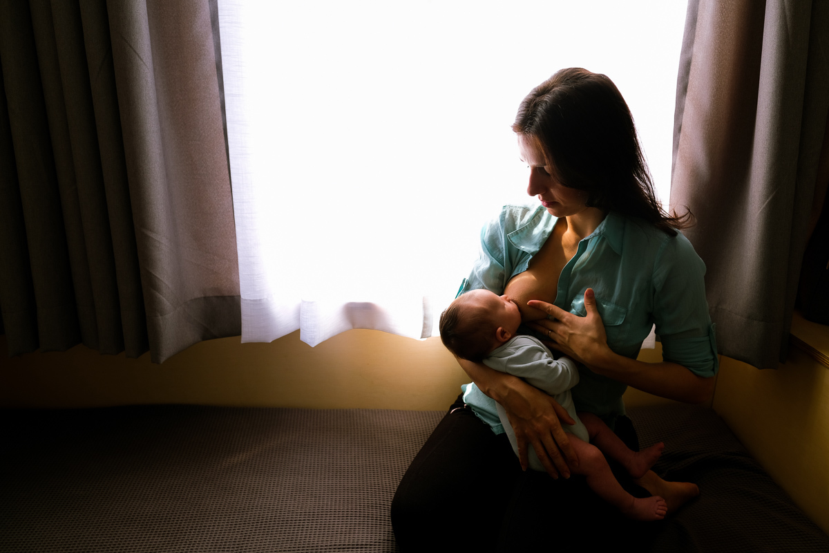 mãe amamentando o filho em momento de amor e carinho no ensaio newborn lifestyle realizado em casa em florianopolis