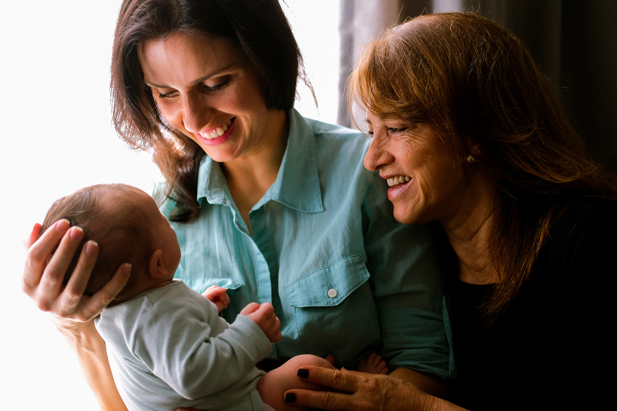 avó e mãe muito felizes com o recém nascido francisco nos braços em ensaio de familia em florianopolis