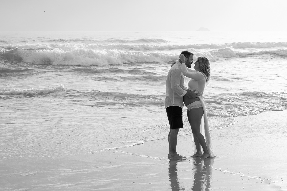 casal se beijando durante ensaio gestante ao amanhecer na praia em Floripa