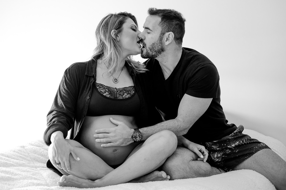 casal se beijando em ensaio gestante na sua cama no conforto de casa