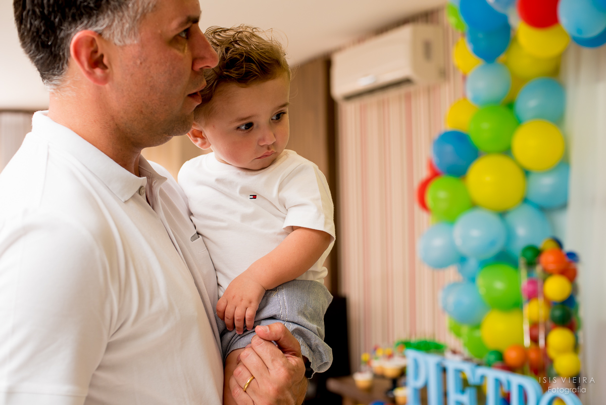o aniversariante e seu pai chegando na festa infantil de 1 ano vendo a decoração da mesa de doces decorada por miss festas com o tema bolas coloridas