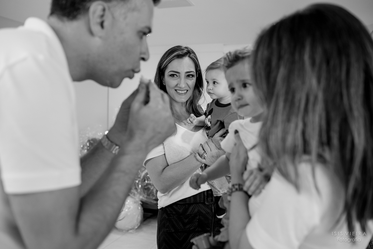 o pai do aniversariante sopra um salgadinho feito pela empresa miss festas para o aniversariante que está completando 1 aninho provar e a mamãe olha com carinho e amor