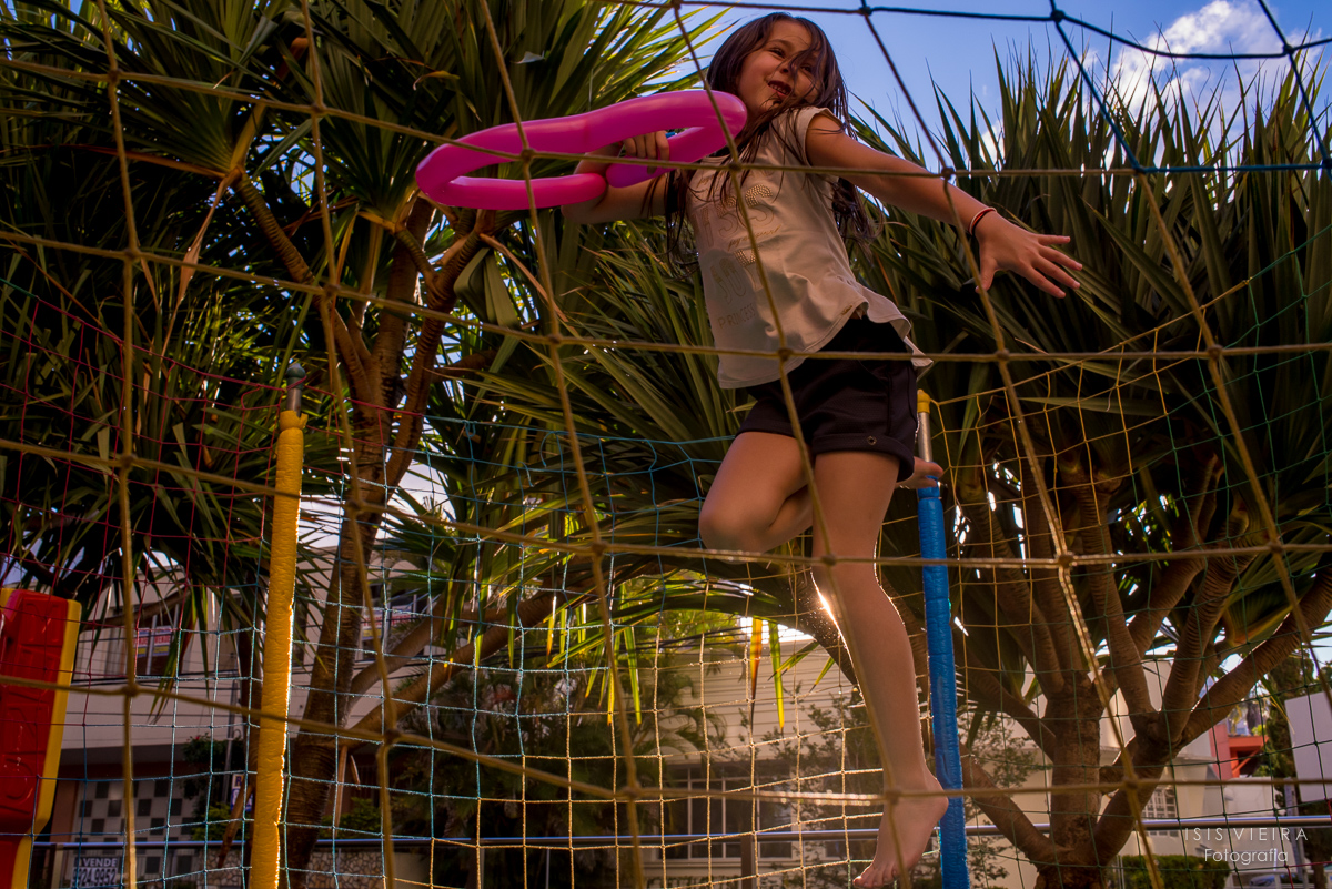 menina brincando no pula pula segurando balões coloridos em forma de coração