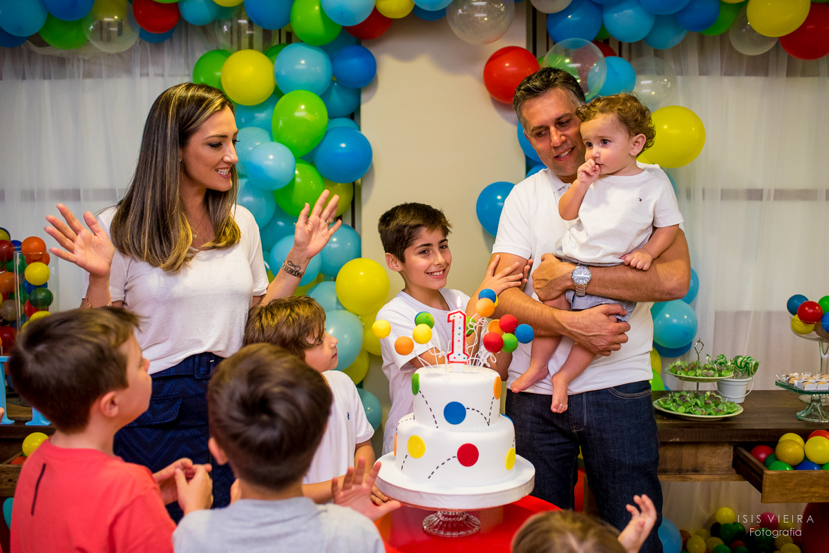 família muito feliz reunida junto com muitas crianças ao redor do lindo bolo infantil para comemorar o primeiro aninho do pietro