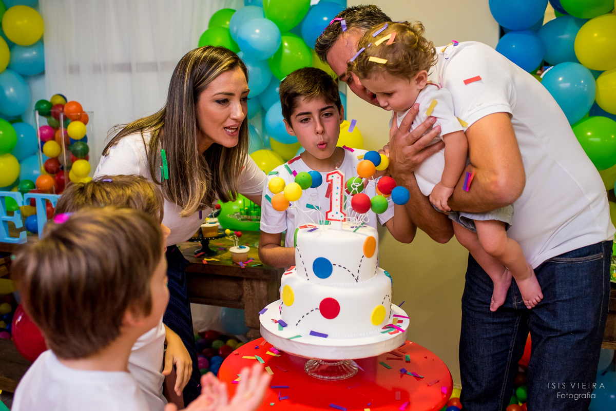 família unida assoprando a velinha do lindo bolo infantil do primeiro aniversário do pequeno pietro