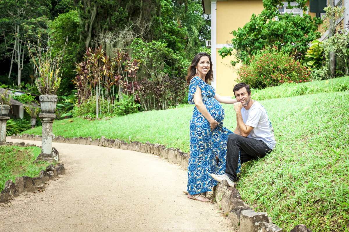 casal posando em gramado de casa amarela em ensaio de gestante