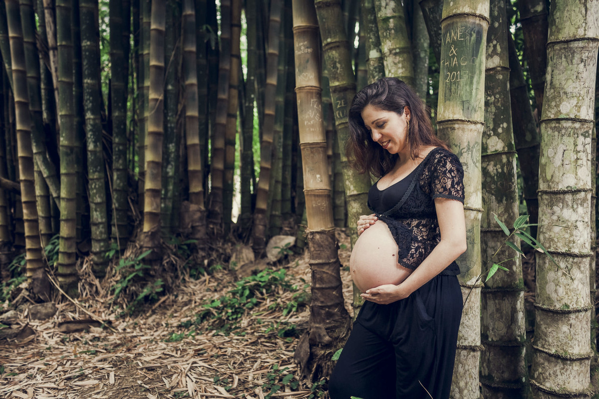 gestante acariciando a barriga encostada em bambuzal no jardim botânico do rio de janeiro