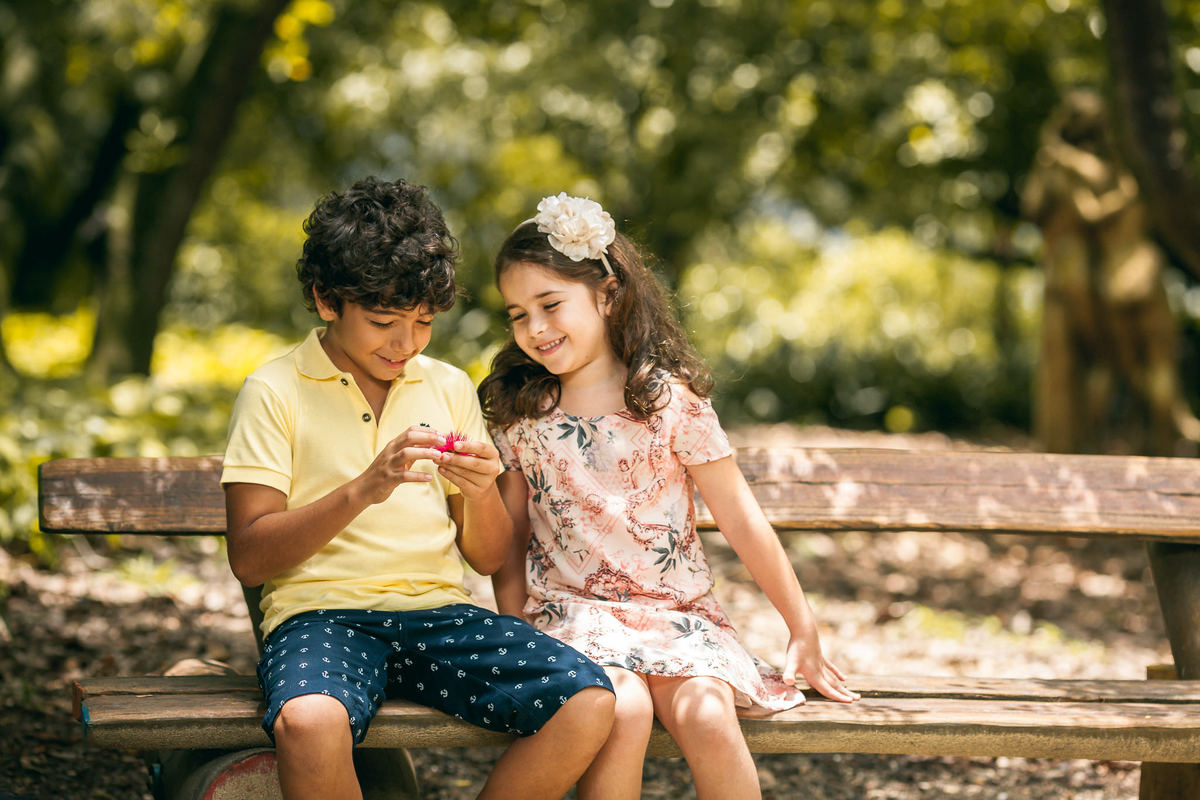 crianças sentadas em bando olhando para flores