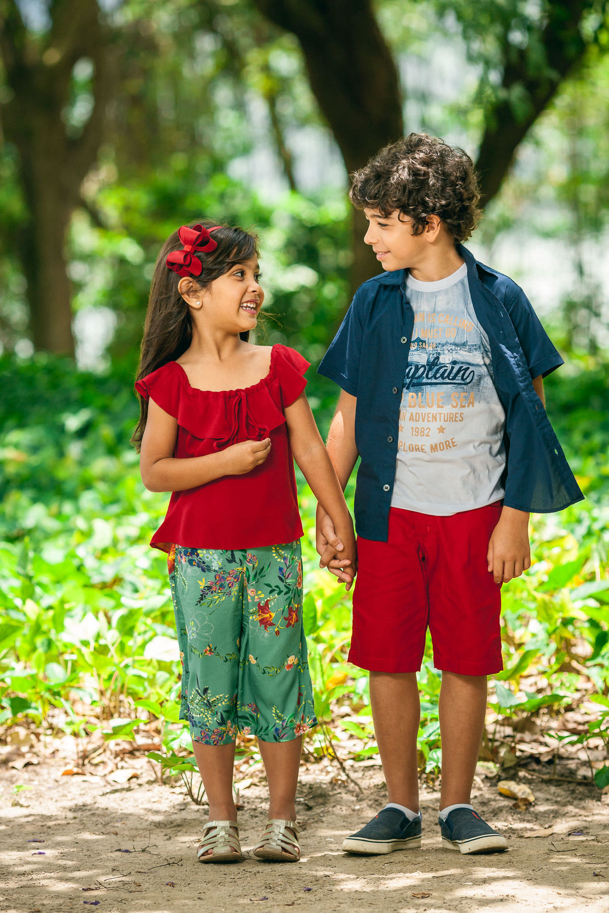 crianças posando de mãos dadas e trocando olhares em campanha de moda infantil