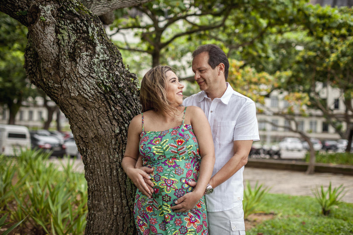 pai e mãe gestante se olhando em book fotográfico realizado na praia vermelha perto do pão de açucar