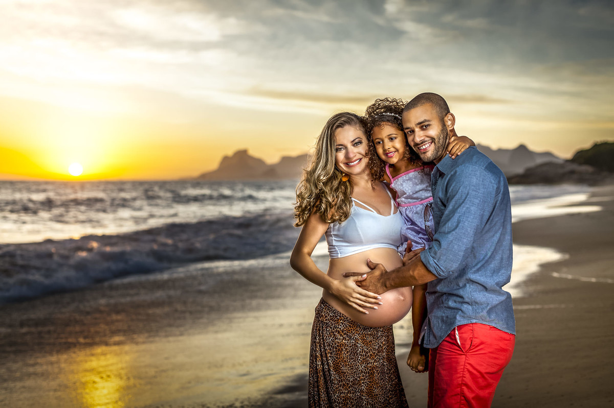 Família de Gestante abraçados na praia em bonito por do sol