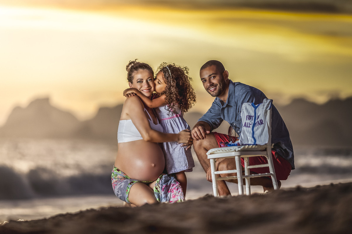 Gestante dando carinho para a filha com cadeirinha do filho esperando-o