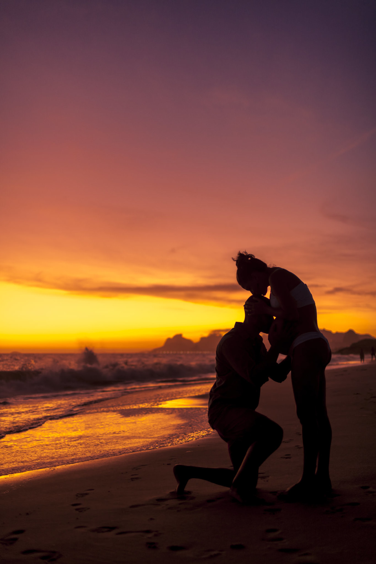 Pai beijando barriga de mamãe gestante em por do sol