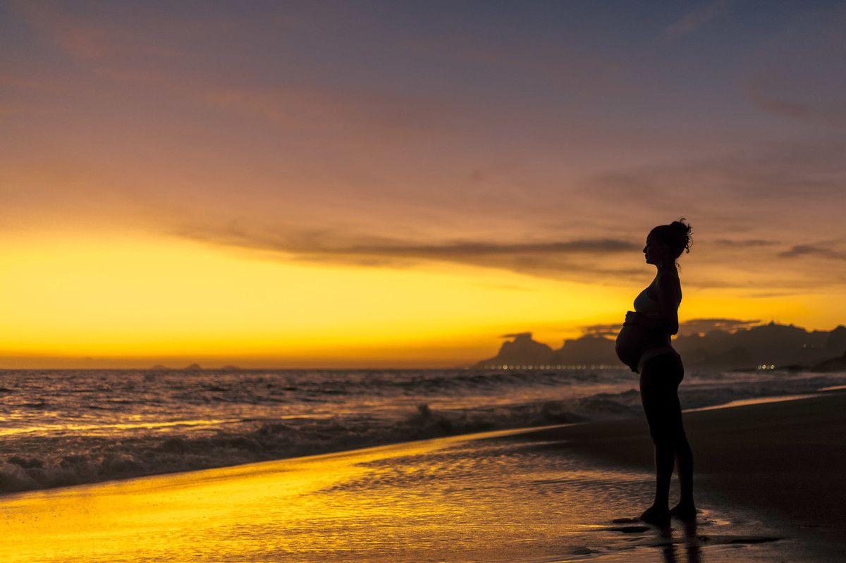 Gestante contemplando por do sol na praia